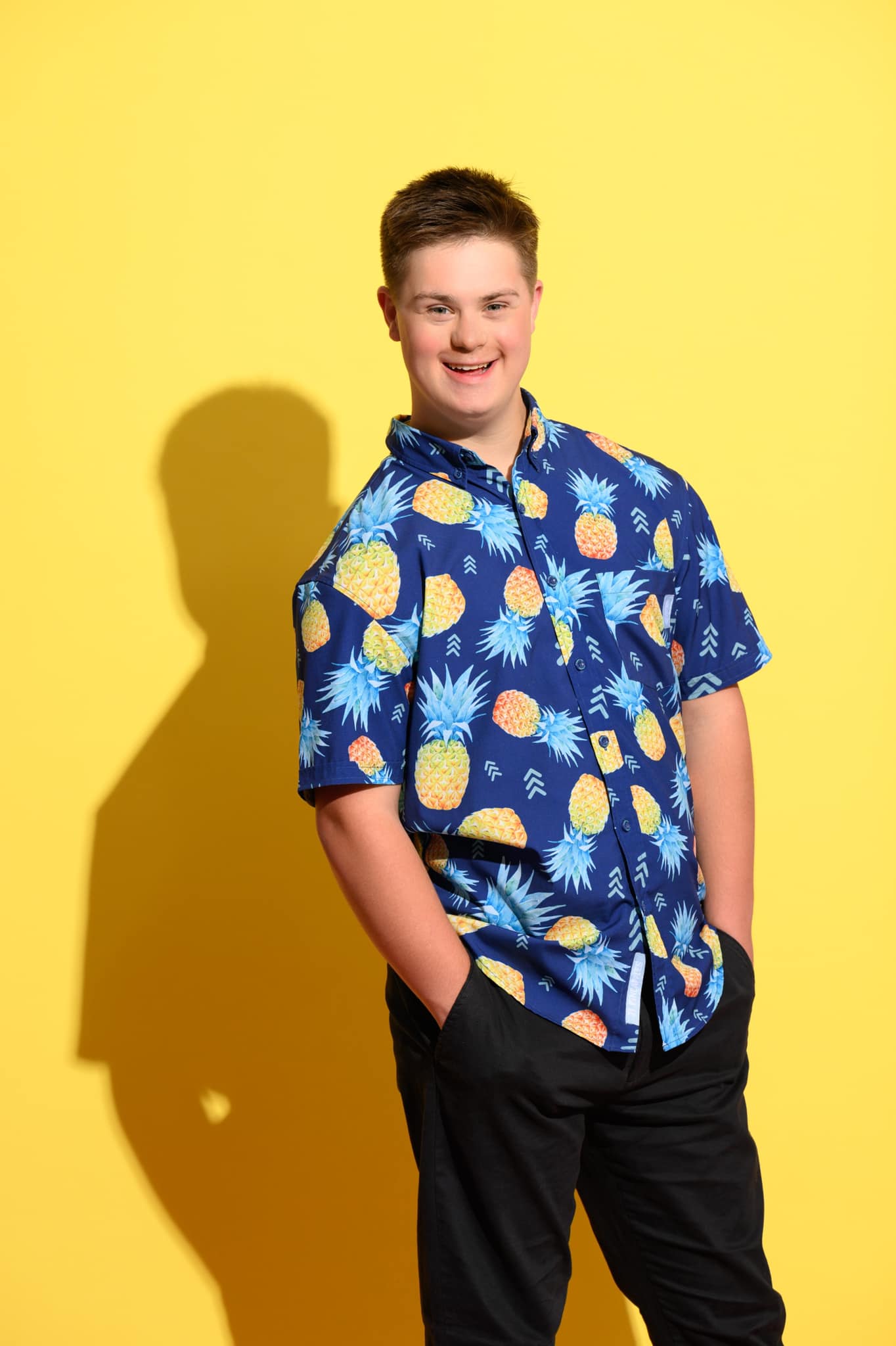 Nate Simon wearing a blue shirt with pineapple pattern on a yellow background